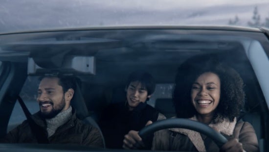Three passengers riding in a vehicle and smiling | Tony Serra Highland Nissan in Highland MI